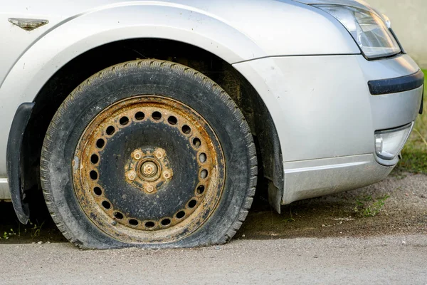 Carro com pneu furado na borda enferrujada velha — Fotografia de Stock