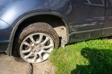 Şehir caddesinde bir trafik kazası, kırık ve boş lastikli bir araba.