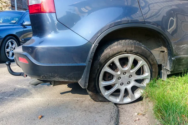 Wypadek drogowy na ulicy miejskiej, samochód z pękniętą i pustą oponą — Zdjęcie stockowe