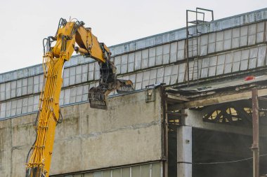 Fabrikanın yeniden inşası için endüstriyel makasla duvar sökülüyor.