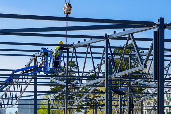 vinç ve makas kaldırma kullanımıyla modern bir binanın metal çerçevesinin birleştirilmesi