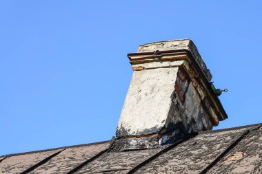 Hasarlı tuğla baca, çatlamış ve tehlikeli bir şekilde eğilmiş.