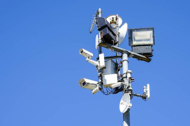 Mavi arka planda birçok güvenlik kamerası ve çeşitli kontrol sistemleri olan bir sütun.
