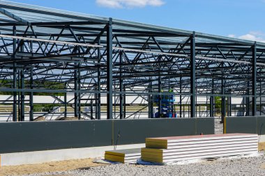 Yeni bir modern sanayi binasının inşası, mavi gökyüzünün arka planında metal kiriş iskeleti.