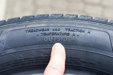 Side view of new tire with tire traction rating, treadwear index and tire outside designation clipart