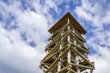 Mavi arka plandaki ahşap kütüklerden yapılmış yüksek gözetleme kulesi