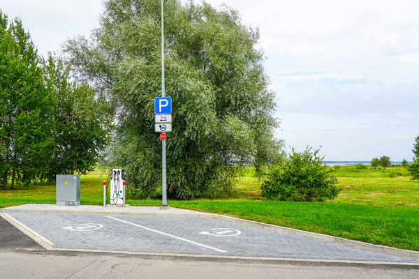 Современная зарядная станция EV с выделенными парковочными местами в зеленой наружной обстановке, способствуя устойчивому транспорту