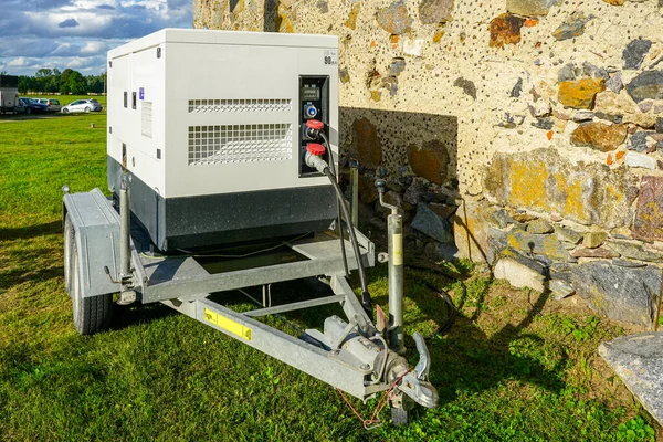 Taşınabilir dizel jeneratör taş duvarın yanındaki karavana monte edildi. İnşaat ve açık hava etkinlikleri için yedek güç kaynağı. Güneş ışığında enerji ekipmanları