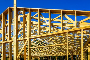 İnşaat sırasında çatı kirişleri ve kirişlerle döşenmiş ahşap evin yakın çekimi. Güçlü yapısal tasarım dayanıklılık ve modern yapı standartlarını güvence altına alır