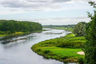 Litvanya 'daki Mezotne Kalesi tepesinden görülen Lielupe Nehri' nin güzel manzarası yemyeşil, orman kıyıları ve su üzerindeki bulutlu gökyüzü yansımaları.