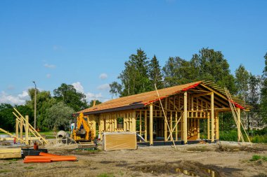 Kereste çerçeve yapım aşamasında görünür çatı yapısı, ahşap kirişler ve güneşli bir günde inşaat malzemeleri.