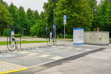 Çoklu şarj noktalarına sahip modern EV şarj istasyonu, işaretli elektrikli araba park alanları ve kentsel ortamdaki güç altyapısı