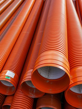 Yığılmış turuncu kıvrımlı plastik boruların yakın çekimi, genellikle inşaat, kanalizasyon ve drenaj sistemlerinde kullanılır.