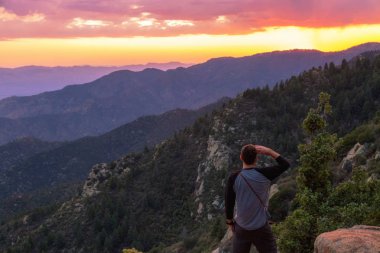 Renkli sunset Bulvarında dağ Doğu Arizona, Amerika Birleşik Devletleri üzerinden bakan gözleri yukarıda el ile erkek turist