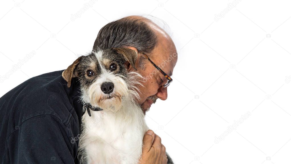 Adult male hugging a cute wire-haired nixed small terrier breed dog that is looking at the camera over white
