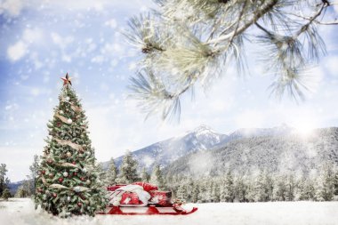 Noel ağacı ve Noel Baba kızağa ormandaki karla kaplı dağlar karlı kış açık sahnesinde hediyelerle. 