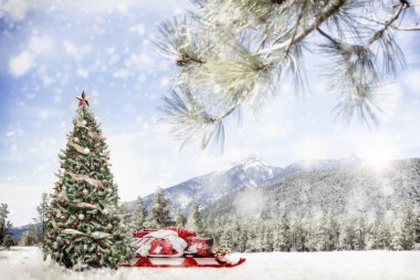 Christmas tree and Santa Claus sleigh with gifts in snowy winter outdoor scene in forest with snow-capped mountains.  clipart