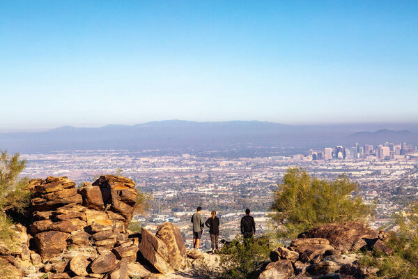 Unidentifiable tourists hike to top of South Mountain to overlook skyline and downtown city buildings
