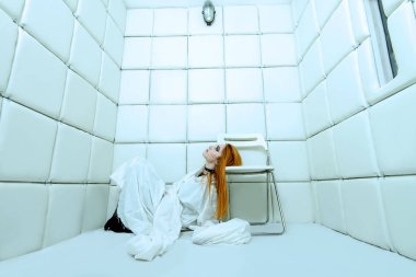 Tımarhane izole bir odada deli gömleği giymiş çılgın bir kız portresi.