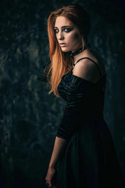 Magnificent woman in black gothic dress over grunge background. Fashion. Gothic style.