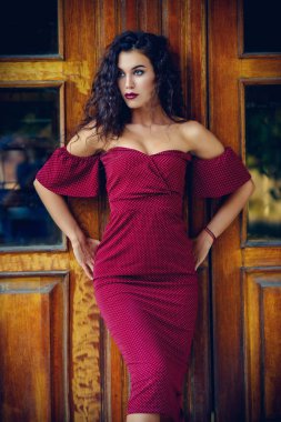 Esmer kadın büyüleyici bir şehir sokak üzerinde zarif bordo elbise giymiş. Güzellik, moda kavramı. Kozmetik ve makyaj.