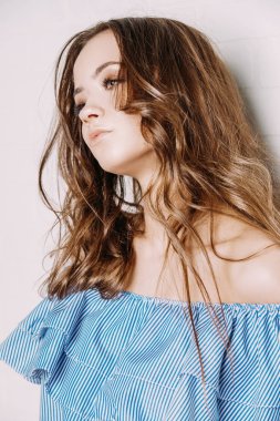 Çekici genç kadın modern gençlik giysili bir beyaz tuğla duvar tarafından duruyor. Güzellik, moda kavramı.