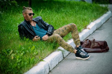 Deri ceketli yakışıklı acımasız adam çim üzerinde yalan söylüyor. Bağımsızlık ruhu.