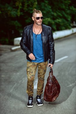 Yakışıklı acımasız adam yolda yürürken deri ceketli. Motorcu adam gezi gidecek. Bağımsızlık ruhu.