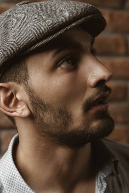 Tuğla duvar arka plan üzerinde bir kap içinde yakışıklı bir brunet adam portresi. Erkek güzelliği, moda. Erkek berber.