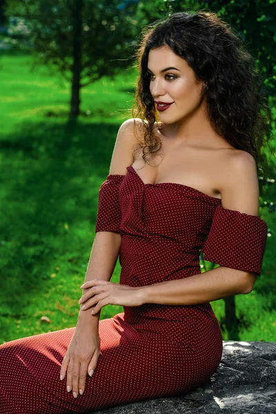 Kadın büyüleyici zarif bordo elbise yaz parkta giyinmiş. Güzellik, moda kavramı.