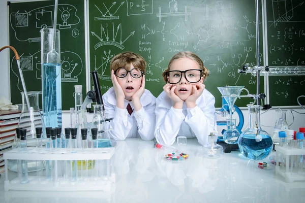 Funny girl and boy scientists are conducting an experiment in the laboratory. Educational concept. Early development of children.