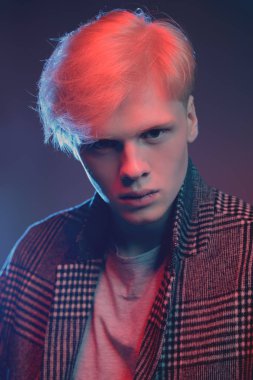 Stüdyoda gri arka plan üzerinde poz yakışıklı bir genç adam sarı saçlı bir ekose ceket giyen portresi. Erkek güzellik ve sağlık.