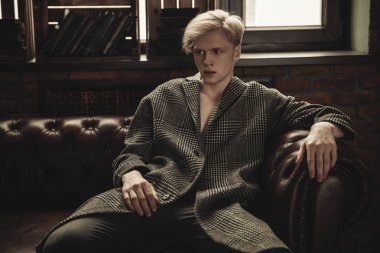 Deri koltuk üzerinde seksi yakışıklı bir adam portresi. Moda vurdu. Erkek güzelliği, moda. 