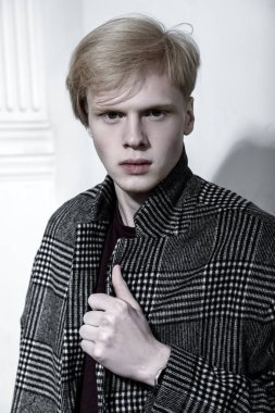 Stüdyoda ışık arka plan üzerinde poz yakışıklı bir genç adam sarı saçlı bir ekose ceket giyen portresi. Erkek güzellik ve sağlık.