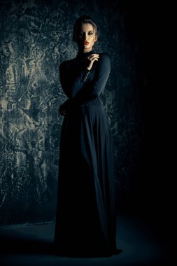 Siyah uygun uzun elbise giyen zarif genç kadın. Güzellik, moda kavramı. Stüdyo vurdu.