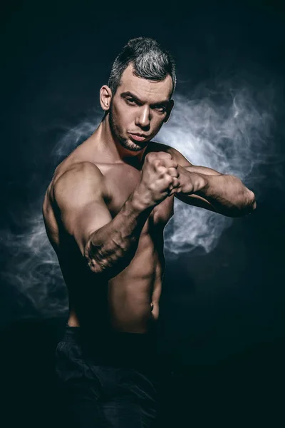 Athlete stands in the fighting stance, ready to strike with his fist. Healthy lifestyle.