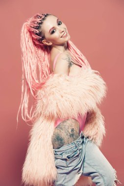 Şık kız pembe dreadlocks pembe bir arka plan üzerinde parlak giysiler içinde poz ile. Güzellik, moda.