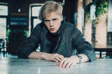 Bir caf bir masada kareli ceket sarışın bir adam portresi. Erkek güzelliği, moda. 