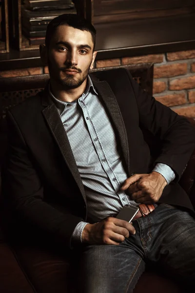 Portrait of a sexy handsome man on a leather sofa. Fashion shot. Men\'s beauty, fashion. Men\'s barbershop, Hairstyle.