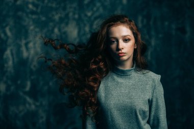 Uzun kıvırcık kırmızı saçlı grunge arka plan üzerinde poz modern on beş yaşındaki kızı. Güzellik, moda.