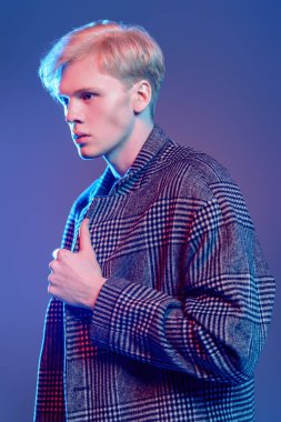 Stüdyoda gri arka plan üzerinde poz yakışıklı bir genç adam sarı saçlı bir ekose ceket giyen portresi. Erkek güzellik ve sağlık.