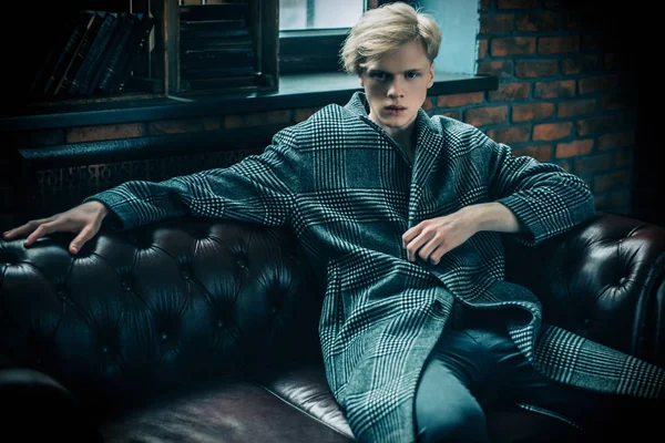 Deri koltuk üzerinde seksi yakışıklı bir adam portresi. Moda vurdu. Erkek güzelliği, moda. 