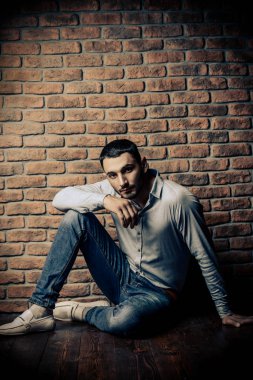 Bir tuğla duvar tarafından poz yakışıklı bir brunet adam portresi. Erkek güzelliği, moda. Erkek Berber Dükkanı, saç modeli.