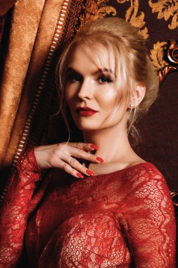 Kırmızı Abiye içinde çekici genç kadın bir lüks daire durumda. Klasik vintage iç. Güzellik, moda. Akşam makyaj ve saç.