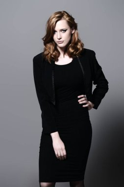 Siyah uygun elbise ve ceket giyen zarif genç kadın. Güzellik, moda kavramı. Stüdyo vurdu.