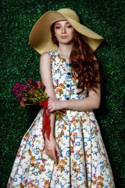 Portrait of a cute girl teenager wearing summer dress and hat over lawny background. Beauty, fashion. clipart