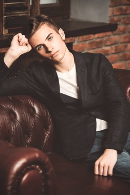 Deri kanepede poz şık giysileriyle akıllı öğrenci çocuk. Moda. Eğitim kavramı.