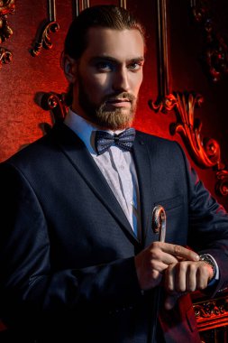 Daireler lüks klasik iç ile poz şık elbiseli iyi giyimli bir heybetli adam portresi. Erkek güzelliği, moda. Saç şekillendirme, berber. 