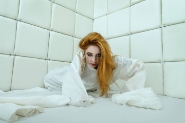 Tımarhane izole bir odada deli gömleği giymiş çılgın bir kız portresi.