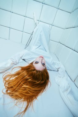 Tımarhane izole bir odada deli gömleği giymiş çılgın bir kız portresi.